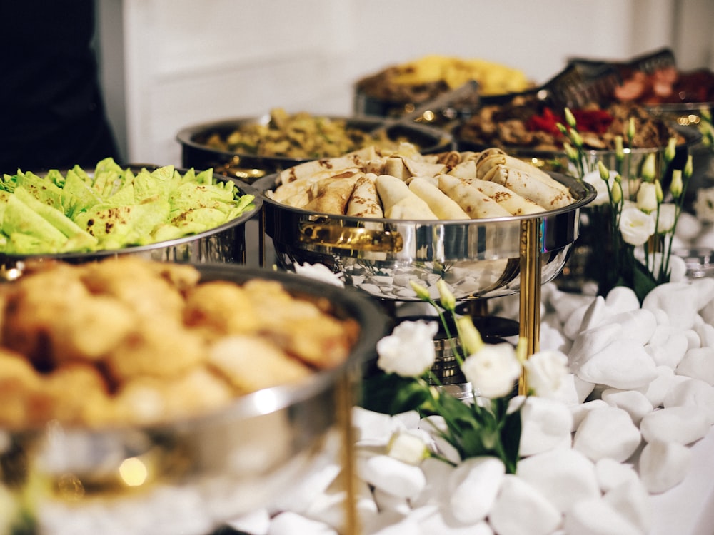 A catering spread laid out in silver dishes with salad and fried starters